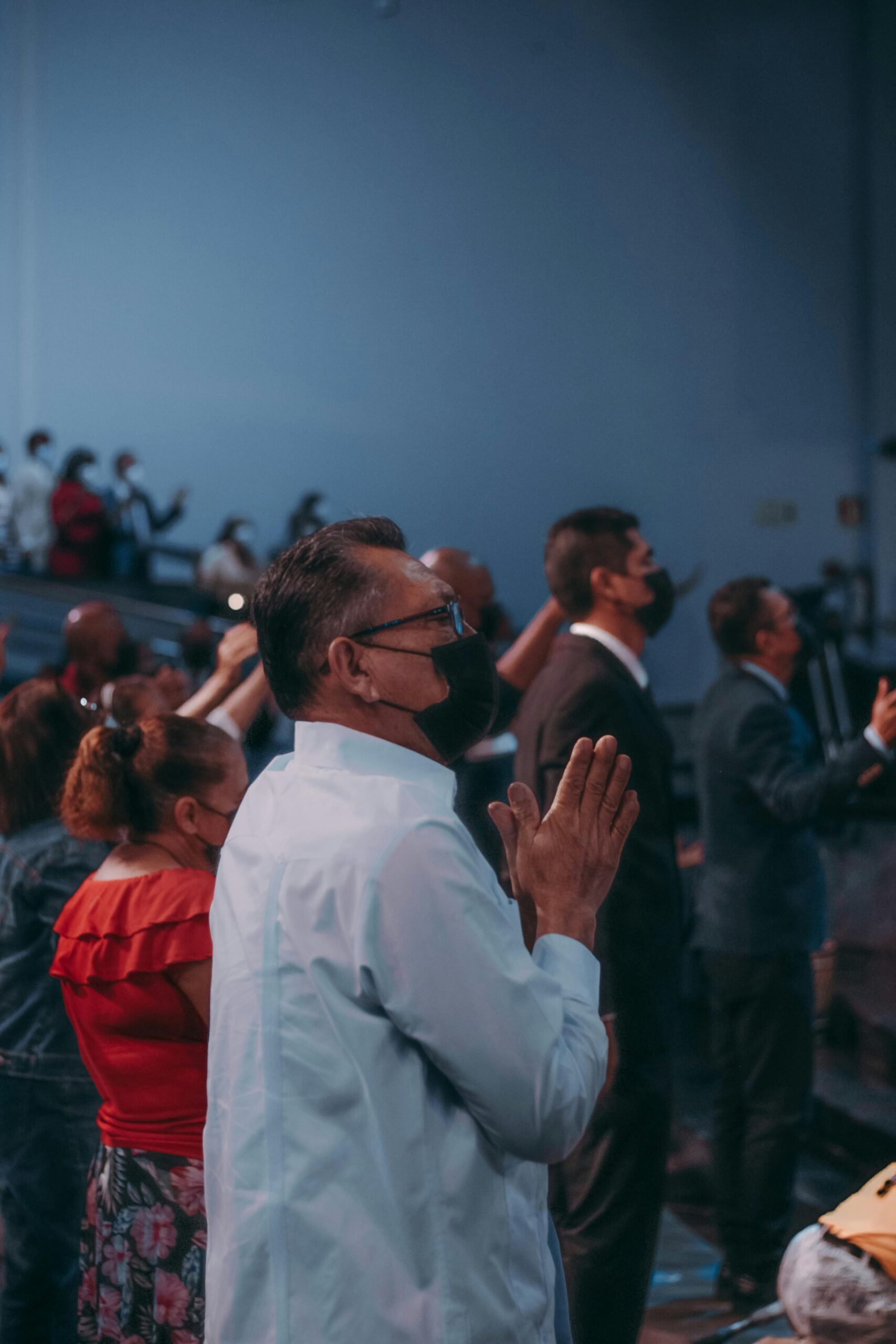 A group of masked individuals participating in a religious service indoors.
